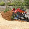 Red and white Takeuchi small track loader moving dirt