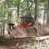 Red and white Takeuchi small track loader moving dirt on an incline