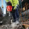 Red and black Hilti electric demolition hammer being used to break up concrete