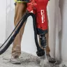 Red and black Hilti electric concrete wet/dry dust vacuum being used while breaking up concrete