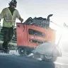 Orange Husqvarna Self-propelled Walk-behind Concrete Saw being used for road construction