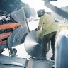 Sierra de calle para concreto autopropulsada Husqvarna naranja y gris con un trabajador cambiándole la cuchilla