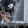 Orange and gray Husqvarna 9 inch concrete Cut-off Saw being used to cut through concrete