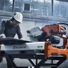 Orange and gray Husqvarna 10 inch electric tile saw used to cut a large piece of tile at a construction site