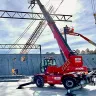 Montacargas de alcance variable de 13,200 lb Magni rojo y negro completamente extendido en un sitio de construcción