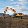 Orange and black Case excavator parked in the dirt with its boom lowered