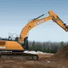 Orange and black Case excavator with its boom raised and dumping dirt into a pile in a wooded area