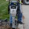 Black and silver Multiquip Mikasa light-duty vibratory rammer in use by a worker in protective gear