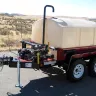 Red and white Multiquip 500 gallon water trailer parked in a lot