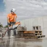 Orange Stihl 14 inch concrete cut-off saw cutting through a concrete block