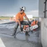 Orange and white Stihl 16 inch cut-off saw cutting through concrete slab