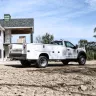 Camion Ford blanc avec carrosserie-atelier stationné sur la terre devant une maison en construction