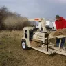 Beige and black FinnCorp straw blower gas powered used by a man on the field
