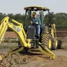 yellow backhoe anchored into dirt on a worksite