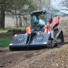 skid steer with a rockhound attachment on a dirt jobsite
