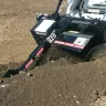 skid steer using a trencher attachment in dirt